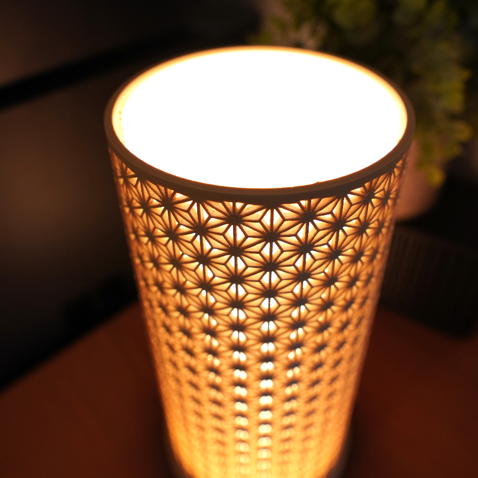 Decorative lamp with intricate cut-out design on a wooden surface.