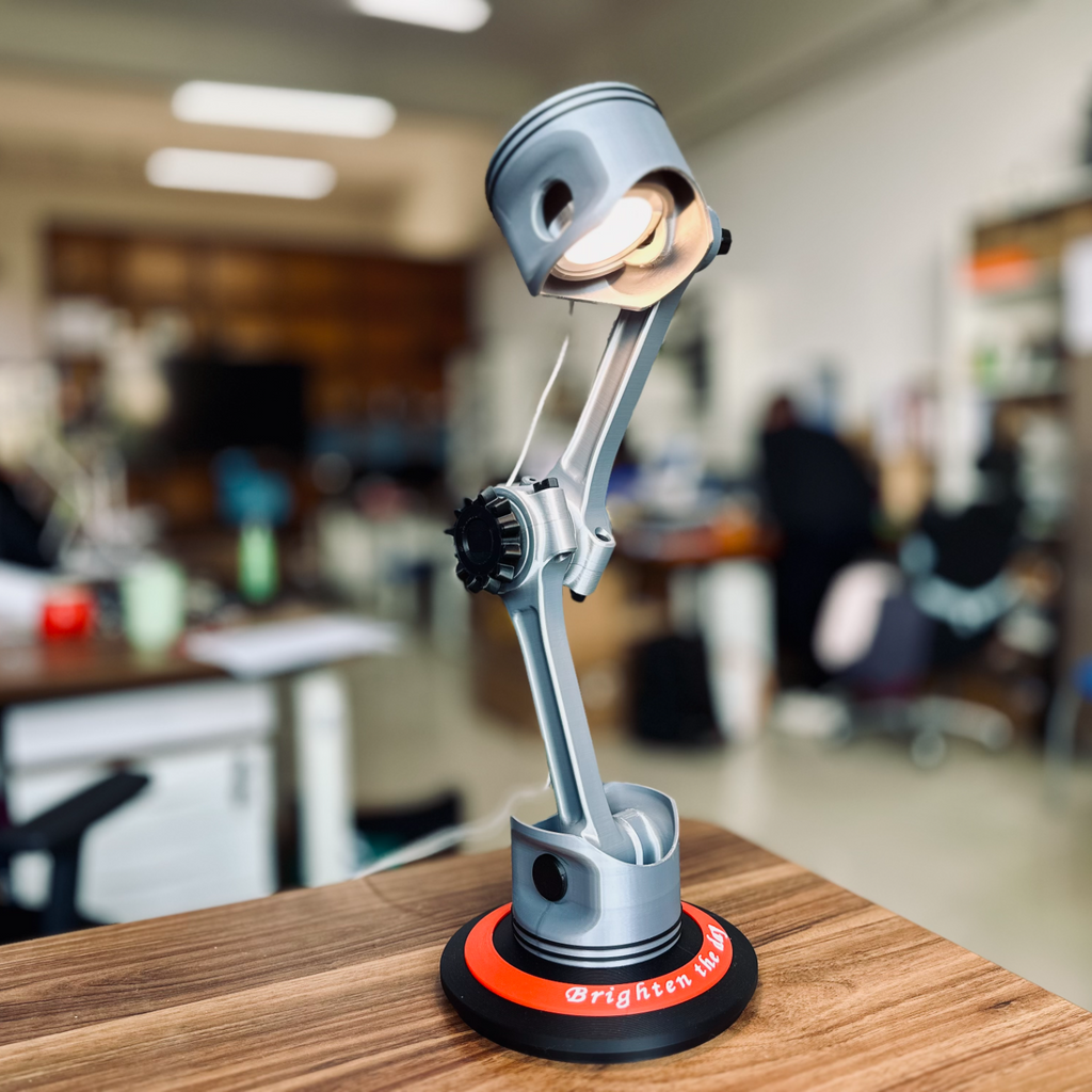 Piston desk lamp on a wooden surface with a blurred office background
