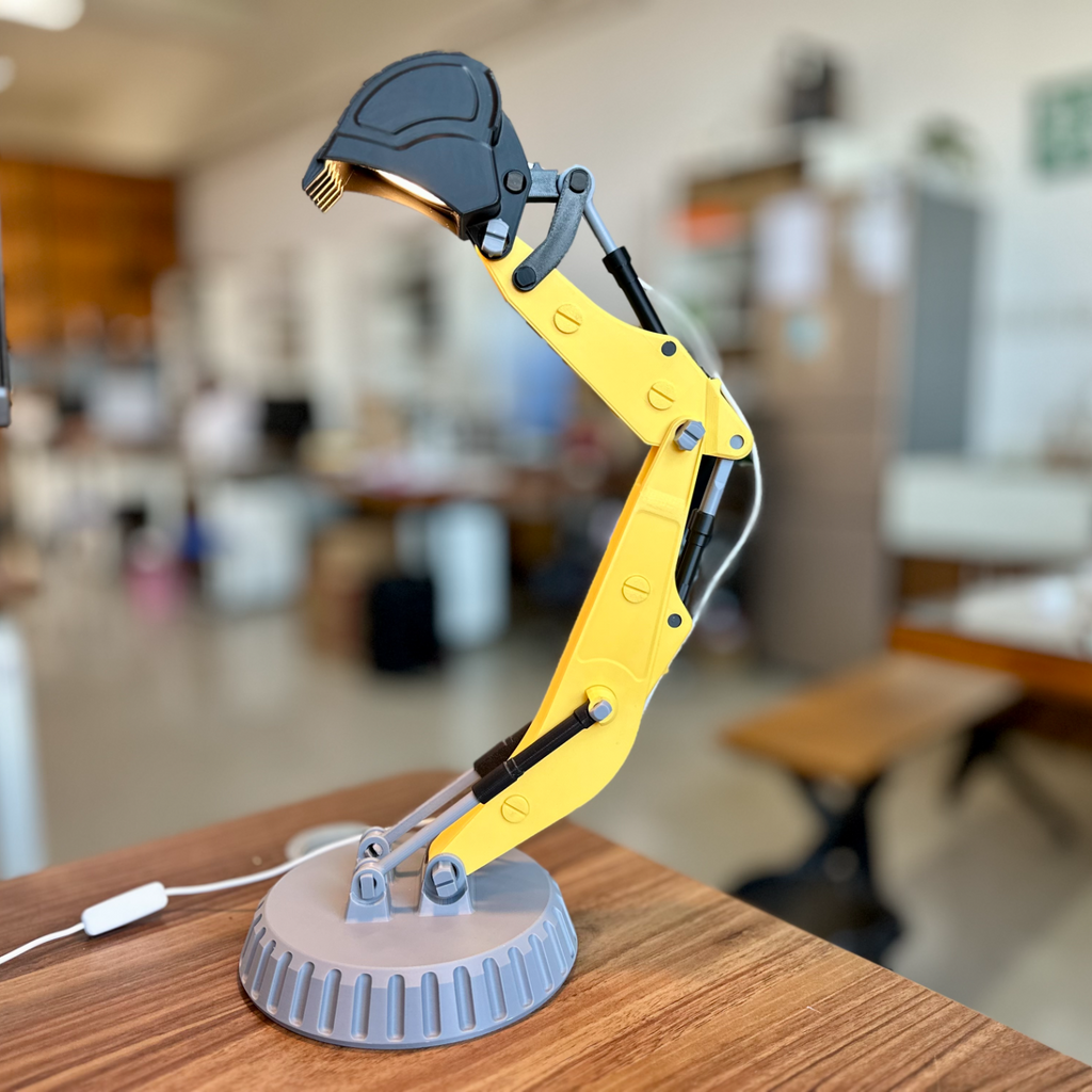 Yellow robotic arm lamp on a desk with a blurred office background